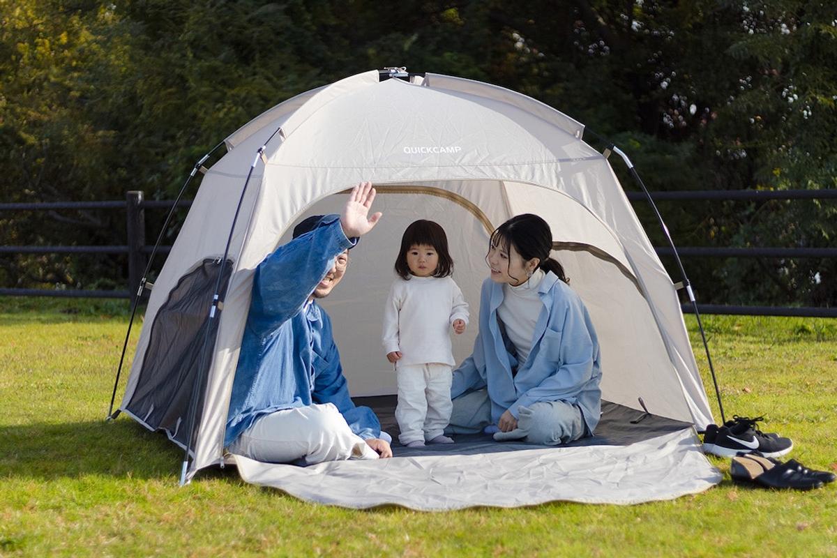 クイックキャンプのコンパクトシェードの中から手を振る男性とその家族