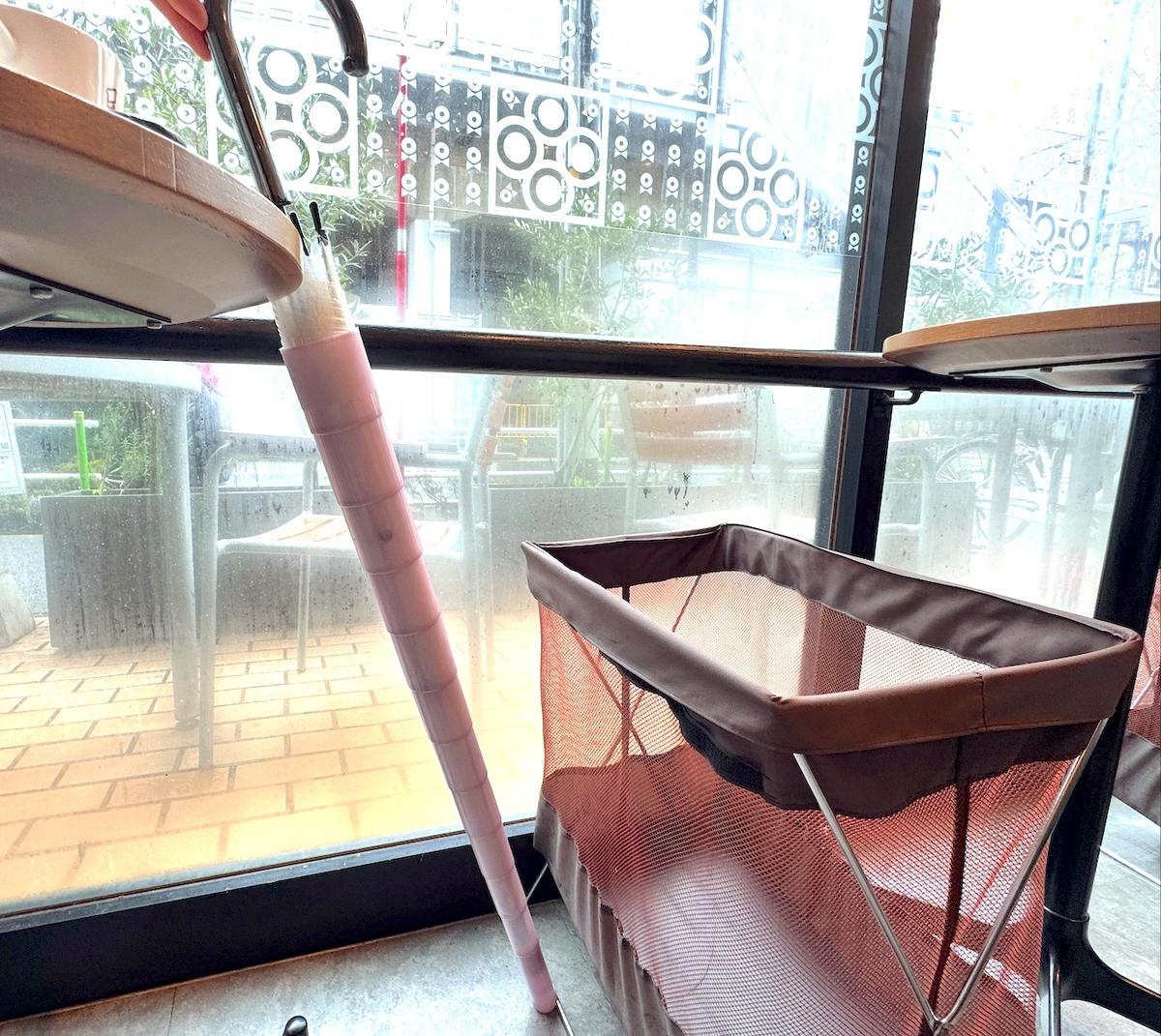 雨の日のカフェの店内で伸縮傘ケースに入れたビニール傘