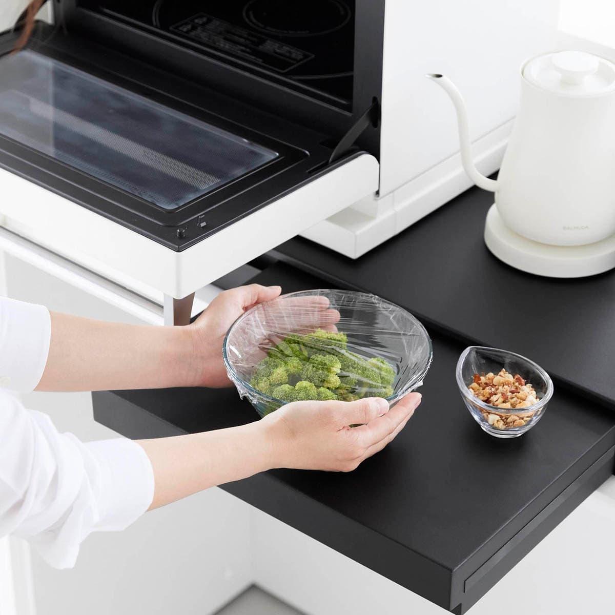 山崎実業の「リバーシブルキッチン家電下スライドテーブル&引き出し タワー W80」でラップをかけているところ