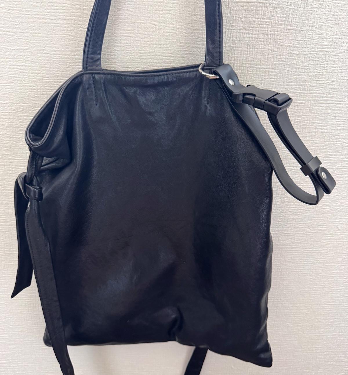 黒い肩掛けカバンの取って部分に3COINSのジャケットホルダーが付いている