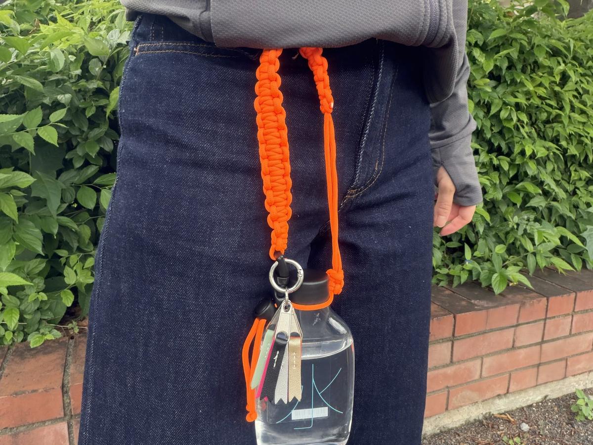 ドリンクチャームを装着した無印良品「水ボトル」をベルトループに通して持ち歩く様子