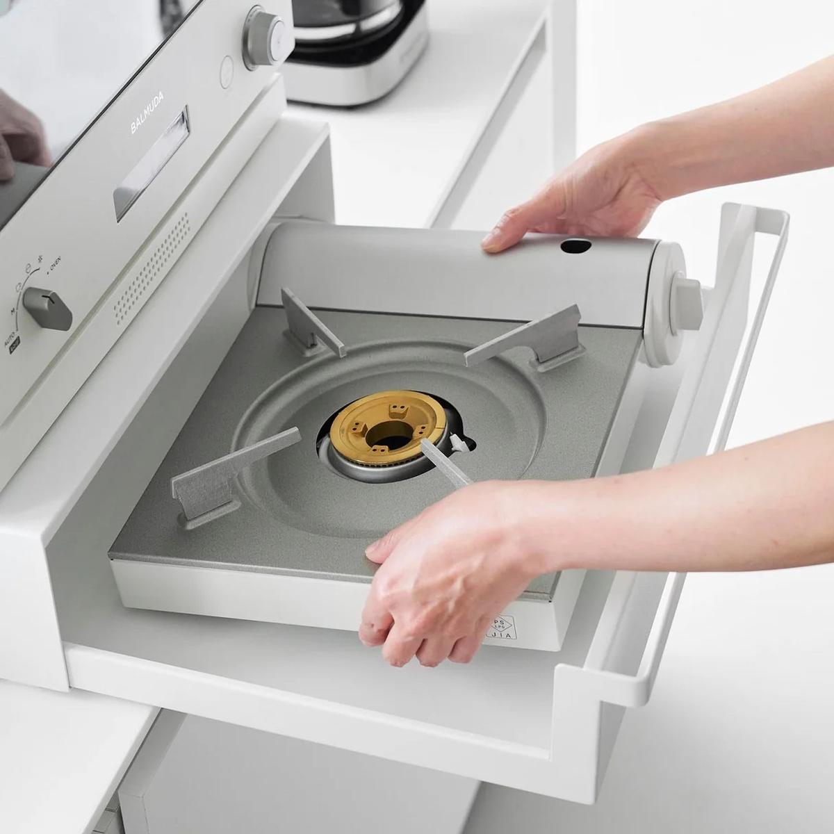 山崎実業「カセットコンロが入る家電下ラック タワー 1段」からカセットコンロを取り出している様子
